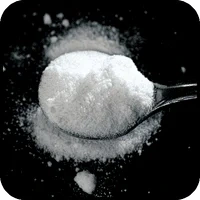 White crystalline amino acid powder on a black spoon